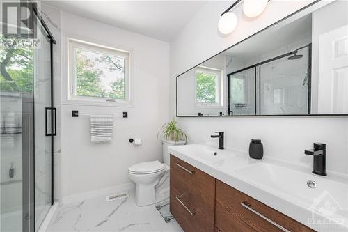 The primary en-suite features a spacious shower with a sliding glass door, a versatile double-sink vanity, a linen closet, and abundant natural light. - 1659 Orford Crescent, Ottawa, ON - Indoor Photo Showing Bathroom