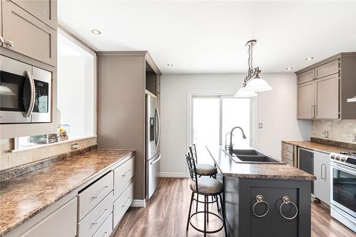 Modern kitchen with double sink, island seating, pot lights and 5 appliances: fridge with lower freezer, gas stove, mircowave, dishwasher, bar fridge, neutral decor. - 47 Simson Avenue, Simcoe, ON - Indoor Photo Showing Kitchen With Stainless Steel Kitchen With Double Sink