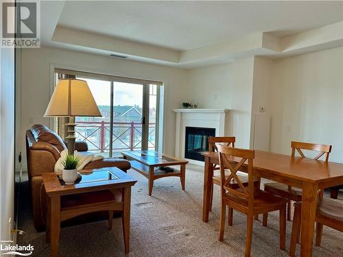 Living area with fireplace and walkout to covered deck - 130 Steamship Bay Road Unit# 305, Gravenhurst, ON - Indoor Photo Showing Dining Room With Fireplace