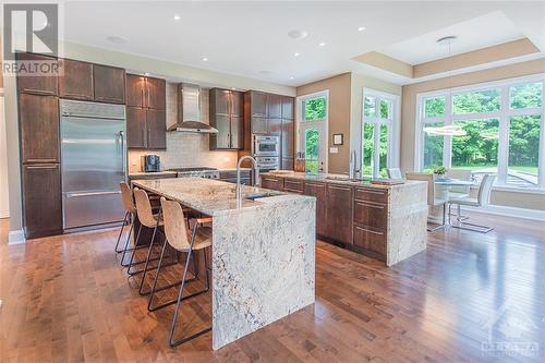 One island offers seating for three and includes an under-mount vegetable prep sink, while the second island features an under-mount double sink with a built-in soap dispenser, a dishwasher with a - 6163 Pebblewoods Drive, Ottawa, ON - Indoor Photo Showing Kitchen With Upgraded Kitchen