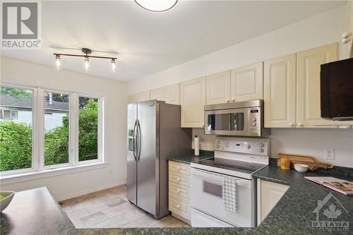 The kitchen has a large window with views of the landscaped yard. - 4405 Ashcroft Court, Ottawa, ON - Indoor Photo Showing Kitchen