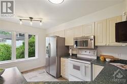 The kitchen has a large window with views of the landscaped yard. - 