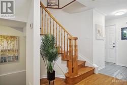 The bright hallway features an elegant hardwood staircase and direct access to the lower level. - 