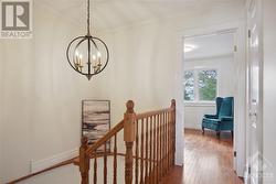 The bright stairway with its hardwood floor features an elegant chandelier. - 
