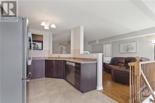 The modern kitchen boasts dark wood cabinets, a white tile backsplash, and an eating area. - 210 Rolling Meadow Crescent, Ottawa, ON 