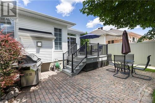 Step outside to your serene, fenced backyard with a deck, interlock patio, and sprinkler system. - 1854 Springridge Drive, Ottawa, ON - Outdoor With Deck Patio Veranda With Exterior