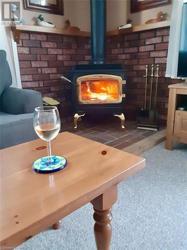 Stunning wood stove with corner brick & wood mantle. - 5 Mill Point Road, North Bruce Peninsula, ON - Indoor With Fireplace