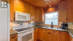 Open concept kitchen/dining/living room with picture windows and gas fireplace overlooking the lake. - 