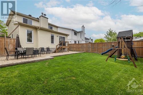 Step outside to the fully fenced backyard with an interlock patio, lush green grass and play structure. - 1454 Shawinigan Street, Ottawa, ON - Outdoor With Deck Patio Veranda With Backyard