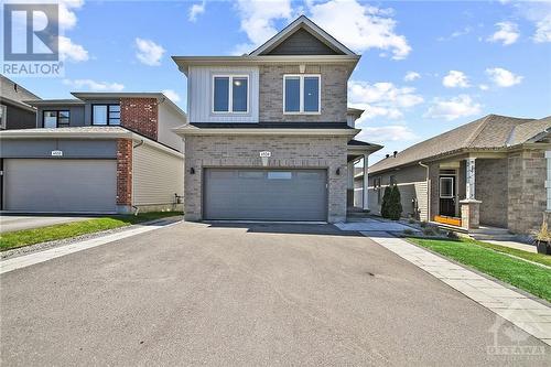 Oversized double laneway with interlock border and synthetic turf - 4530 Kelly Farm Drive, Ottawa, ON - Outdoor With Facade