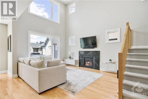 Open to above living room with custom granite fireplace surround and custom built ins for storage - 4530 Kelly Farm Drive, Ottawa, ON - Indoor Photo Showing Living Room With Fireplace