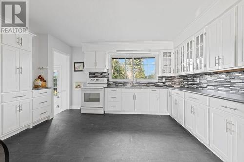 Kitchen looking north.  Lovely modern white cabinetry with black countertops & matching black vinyl floor, all in mint condition.  5 cabinets with glass doors are original however match    newer c - 815 Joseph Street E, Cardinal, ON - Indoor Photo Showing Kitchen