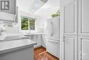 The custom kitchen has been completely redone. The double doors conceal the full size washer/dryer. - 260 Brittany Drive Unit#103, Ottawa, ON  - Indoor Photo Showing Kitchen 