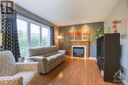 The bright and spacious living room offers a cozy gas fireplace, perfect for relaxing evenings. - 