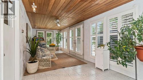 Sunroom with california shutters leads to patio - 21709 Wonderland Road N, Middlesex Centre, ON - Outdoor With Exterior