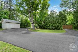 New paved driveway (2023) with a gate and the large shed at the front of the home. - 