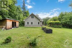 Rear of the home with the raised garden beds and shed for wood. - 