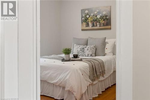 The first charming bedroom features beautiful hardwood floors and offers a tranquil view over the gardens, creating a peaceful and inviting space to unwind and relax. - 1371 3Rd Avenue E, Owen Sound, ON - Indoor Photo Showing Bedroom