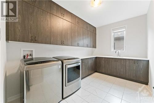 Massive upstairs laundry with lots of extra cabinets; sink and window - 700 Coast Circle, Manotick, ON - Indoor Photo Showing Laundry Room