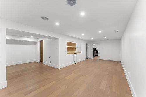 Media room. Wine bar on left, wet bar mid-frame. Large bathroom rear left. Bedroom/office/den rear center. White oak flooring throughout. Utility room. - 5427 Anthony Place, Burlington, ON - Indoor Photo Showing Other Room