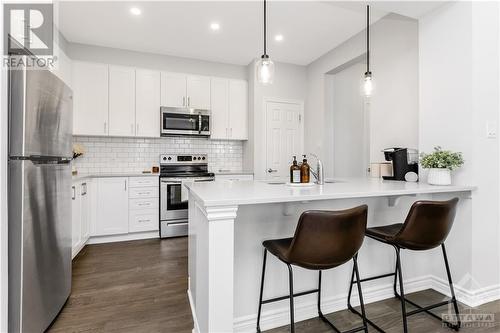 The bright white kitchen is a chef’s delight, featuring generous counter space, elegant cabinetry, and sleek stainless steel appliances. - 97 Ballinora Lane, Ottawa, ON - Indoor Photo Showing Kitchen With Stainless Steel Kitchen With Upgraded Kitchen