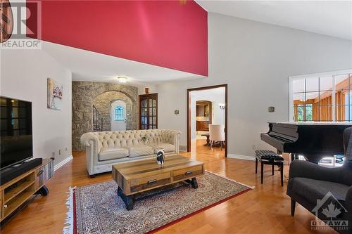 The living room projects warmth and sophistication with its vaulted ceilings and striking wood-burning fireplace - 1390 Millburn Crescent, Ottawa, ON - Indoor Photo Showing Living Room