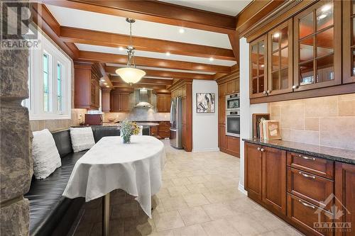 The heart of the home is the expansive eat-in kitchen, a chef’s paradise boasting custom cabinetry, stainless steel Miele and Bosch appliances, a tiled backsplash, and luxurious granite countertops - 1390 Millburn Crescent, Ottawa, ON - Indoor Photo Showing Dining Room