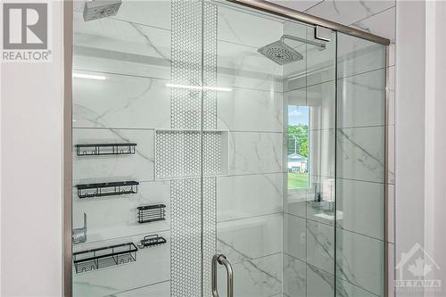 The walk-in shower is a true showstopper, boasting dual shower heads for a spa-like experience. The shower is adorned with pebbled detail tiles, adding texture and a natural element to the space, - 708 Geneva Crescent, Embrun, ON - Indoor Photo Showing Bathroom