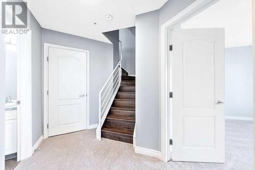 Hardwood stairs lead down to new ccarpeting - 1203, 1514 11 Street Sw, Calgary, AB - Indoor Photo Showing Other Room