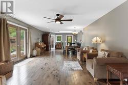 Living room with ceiling fan with notable chandelier, dark wood-type flooring, and a healthy amount of sunlight - 