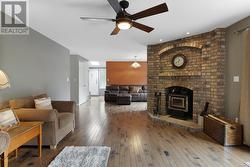 Living room with light hardwood / wood-style flooring, ceiling fan, and a fireplace - 