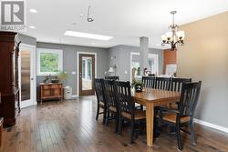 Dining space featuring a notable chandelier, a skylight, and dark hardwood / wood-style flooring - 