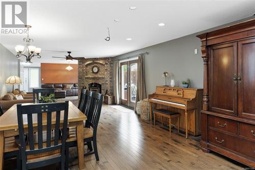 Dining space featuring ceiling fan with notable chandelier, a fireplace, and light hardwood / wood-style flooring - 773 Terrien Way, Parksville, BC - Indoor Photo Showing Dining Room