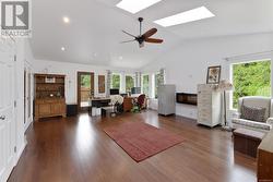 Living room with high vaulted ceiling, a skylight, ceiling fan, and dark hardwood / wood-style flooring - 