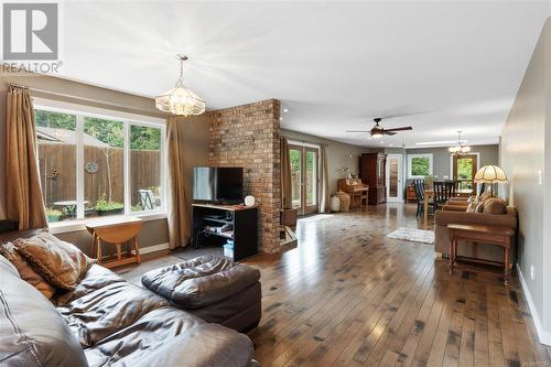 Living room with ceiling fan with notable chandelier, hardwood / wood-style floors, and a wealth of natural light - 773 Terrien Way, Parksville, BC - Indoor Photo Showing Living Room