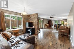 Living room with ceiling fan with notable chandelier, hardwood / wood-style floors, and a wealth of natural light - 