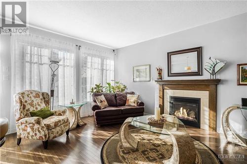 Living room with 9 foot ceilings, hardwood floors & gas fireplace - 715 Hazelnut Crescent, Ottawa, ON - Indoor Photo Showing Living Room With Fireplace