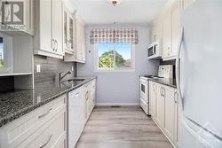 Welcome to a kitchen where style meets functionality in a sunlit embrace. Natural light floods this inviting space through large windows, illuminating the stunning granite countertops - 