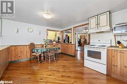 Kitchen with wood walls, light hardwood / wood-style floors, and white appliances - 