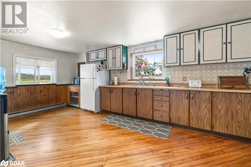 Kitchen with backsplash, a baseboard heating unit, white refrigerator, sink, and light hardwood / wood-style flooring - 1868 County Road 14, Ameliasburg, ON - Indoor Photo Showing Kitchen