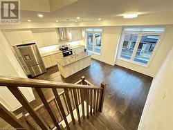 Kitchen featuring dark wood-type flooring, white cabinets, hanging light fixtures, appliances with stainless steel finishes, and a kitchen island - 