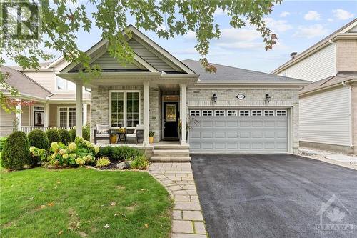 Charming single-story home with a two-car garage, cozy front porch, and beautifully landscaped yard featuring lush greenery and hydrangeas, perfect for peaceful living. - 316 Eckerson Avenue, Ottawa, ON - Outdoor With Deck Patio Veranda With Facade