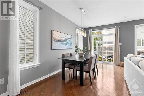 Elegant dining area with large windows and a crystal chandelier, seamlessly flowing into the living space and creating a welcoming environment for dinner parties. - 316 Eckerson Avenue, Ottawa, ON - Indoor Photo Showing Dining Room