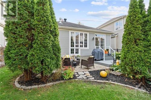 Beautifully landscaped backyard with tall evergreen trees, a stone patio, and plenty of greenery, creating a private and peaceful outdoor retreat. - 316 Eckerson Avenue, Ottawa, ON - Outdoor