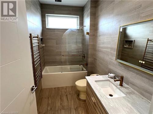 Full bathroom with tile walls, vanity, tiled shower / bath combo, hardwood / wood-style floors, and toilet - 40 Masson Lane, Callander, ON - Indoor Photo Showing Bathroom