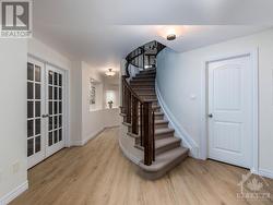 Beautiful Curved staircase to the lower level.  Note the door on the right leads to a storage room and the french doors lead to the home theatre room. - 