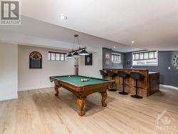 Beautiful Rec Room, perfect size for a pool table, complete with wet bar. Note the lovely new deluxe vinyl flooring. There is also a set of stairs at the back far left that lead to the garage. - 