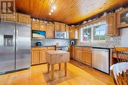 Kitchen with custom cabinetry, tile backsplash, granite countertops, hi-end stainless steel appliance, double stainless steel sink & small built-in work area to right of dishwasher.  Small tv can - 