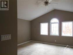 Large, bright primary bedroom with vaulted ceiling and ceiling fan. - 