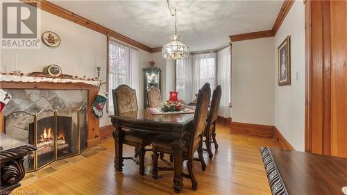 Dining room with a stone fireplace, a chandelier, crown molding, and light hardwood / wood-style floors - 246 Light Street, Woodstock, ON - Indoor Photo Showing Dining Room With Fireplace